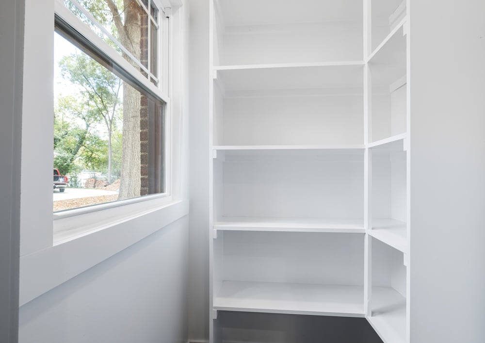 Pantry with white shelves and a open window