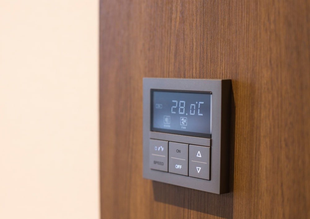 A digital temperature regulator on a wooden wall