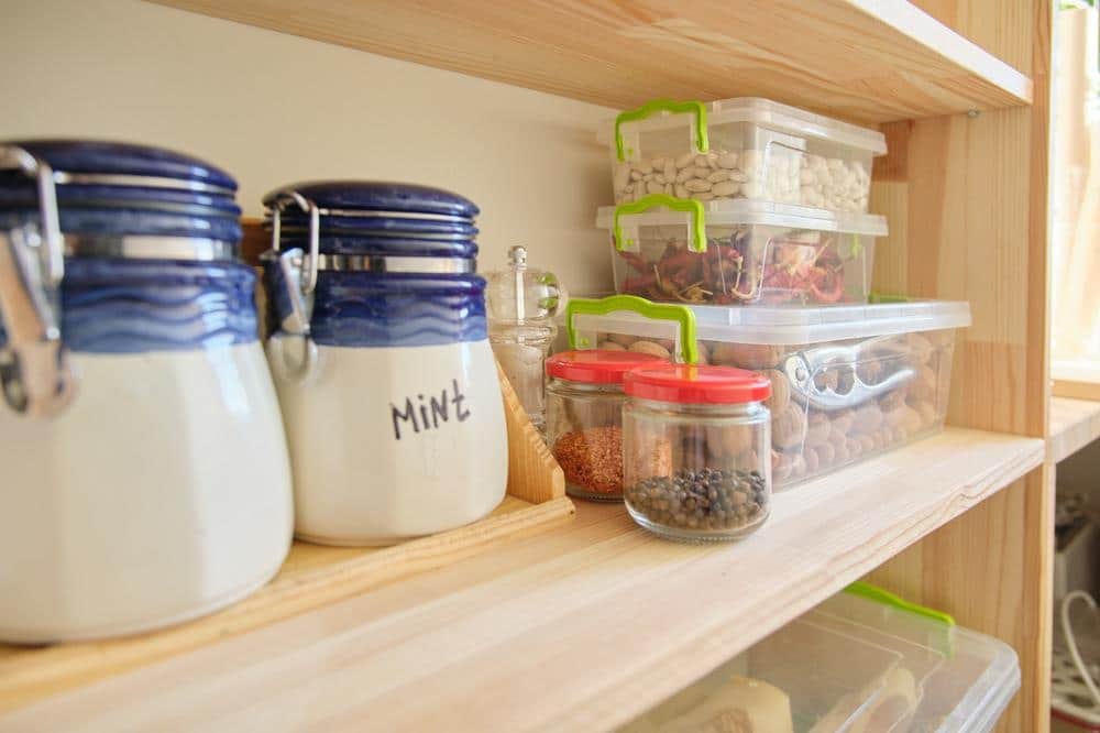 A light wooden pantry shelf with food jars