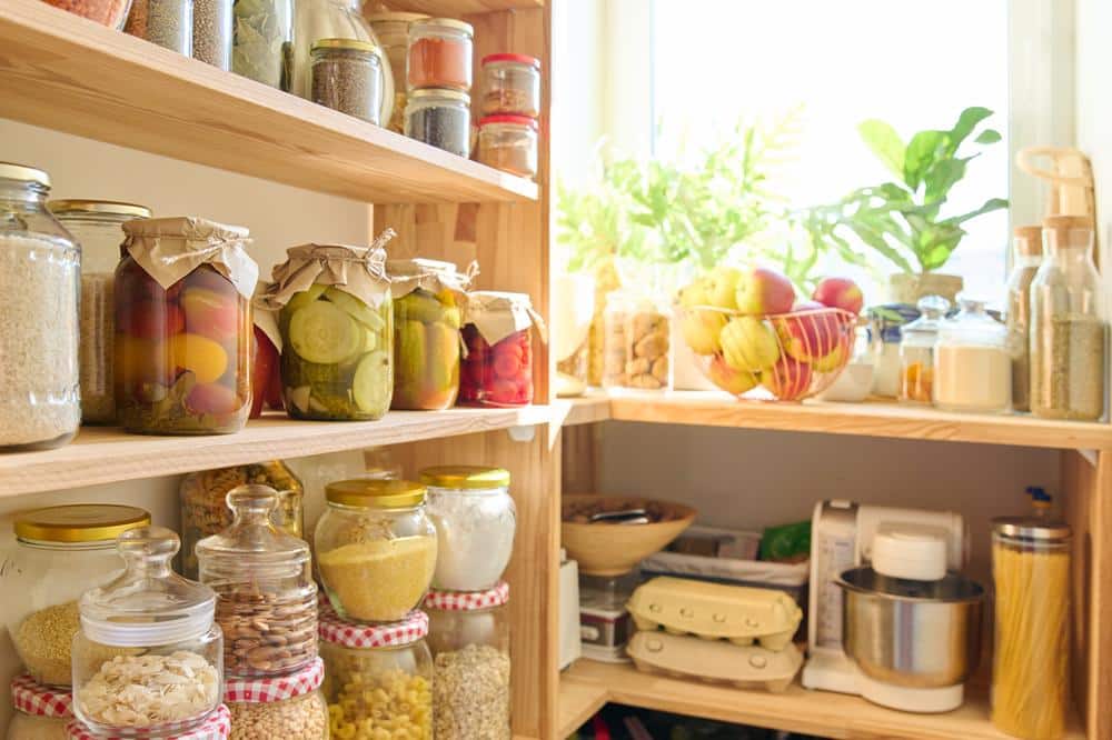 Warm lighted wooden pantry contains jars of food