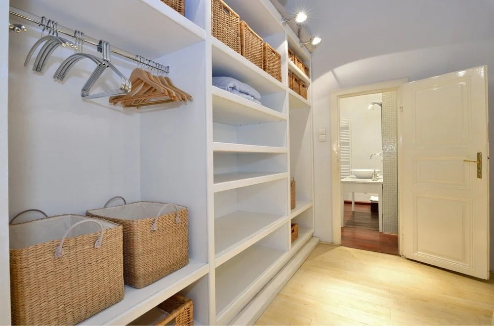 Small walk-in closet with warm lighting and hangs