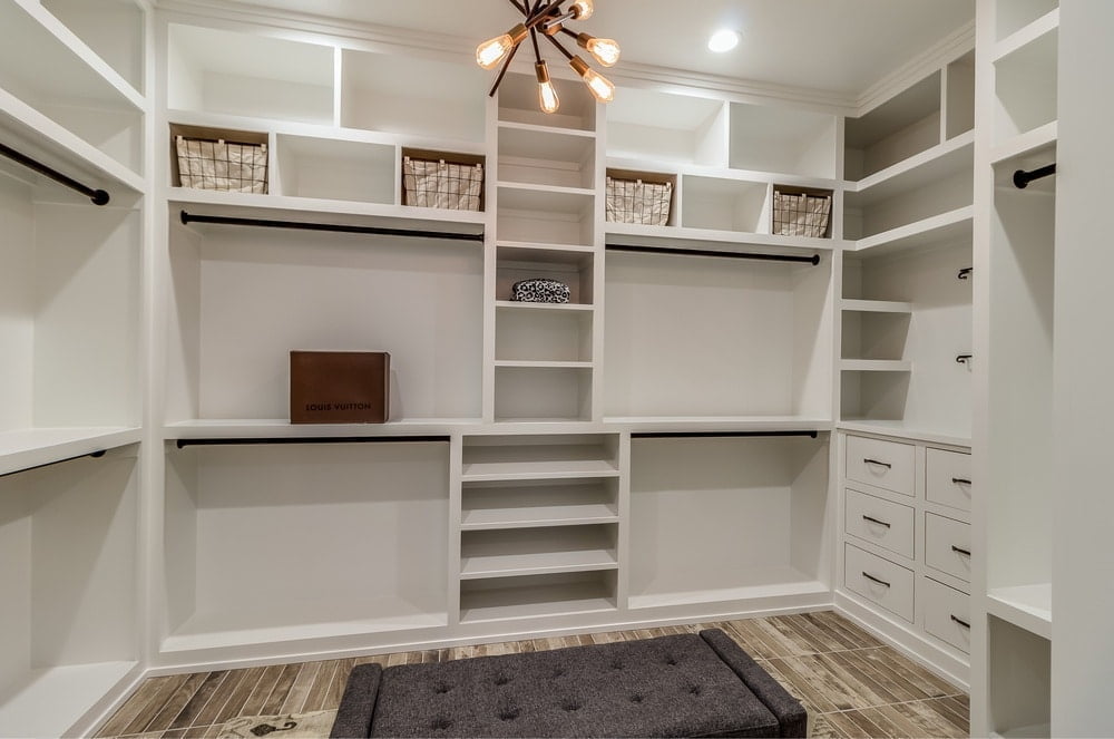 Walk-in closet with display shelves and yellow lighted chandelier