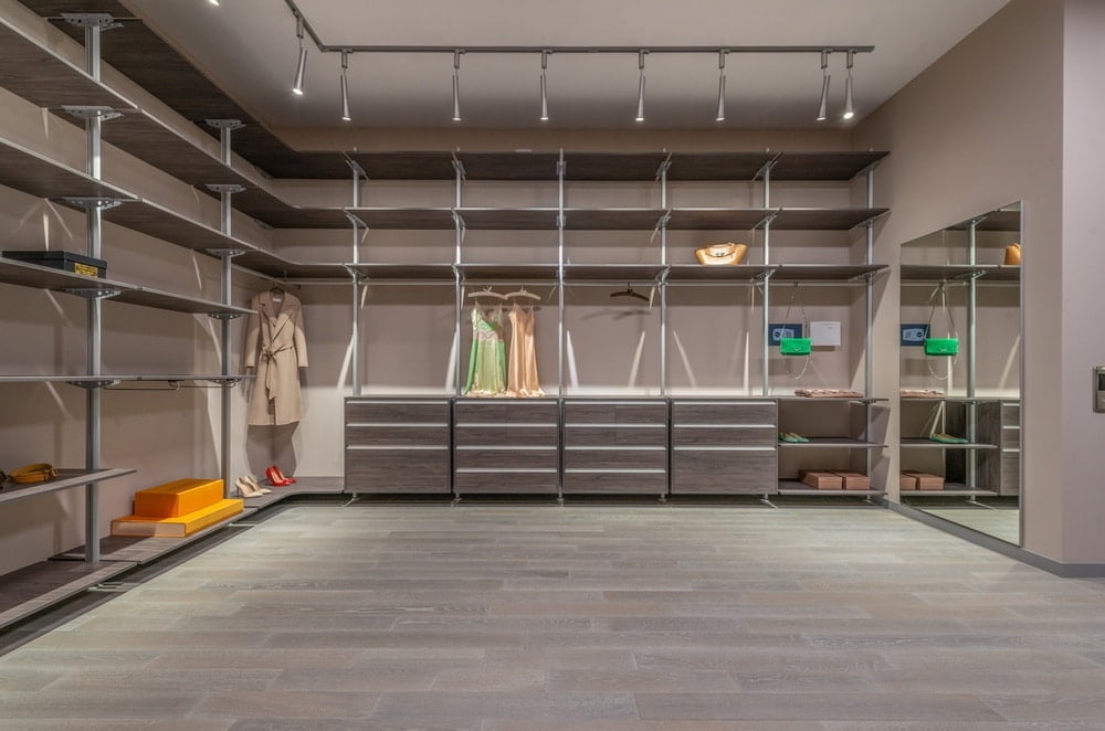 Large neutral colored walk-in closet room with spotlights and shelves