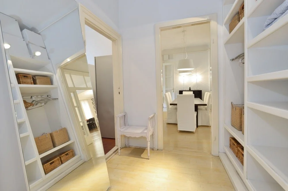 Small walk-in closet with dim lighting and a mirror
