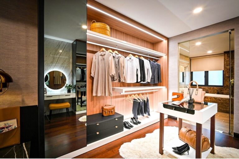 A walk in closet that has hanging racks and clothes inside
