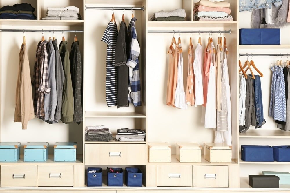 Open closet that has small drawers and clothing racks