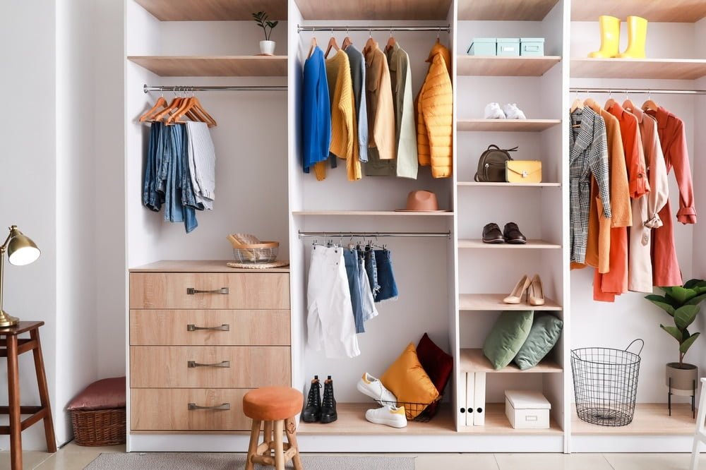 Open closet design with colorful clothes inside and wooden drawers on the bottom shelf