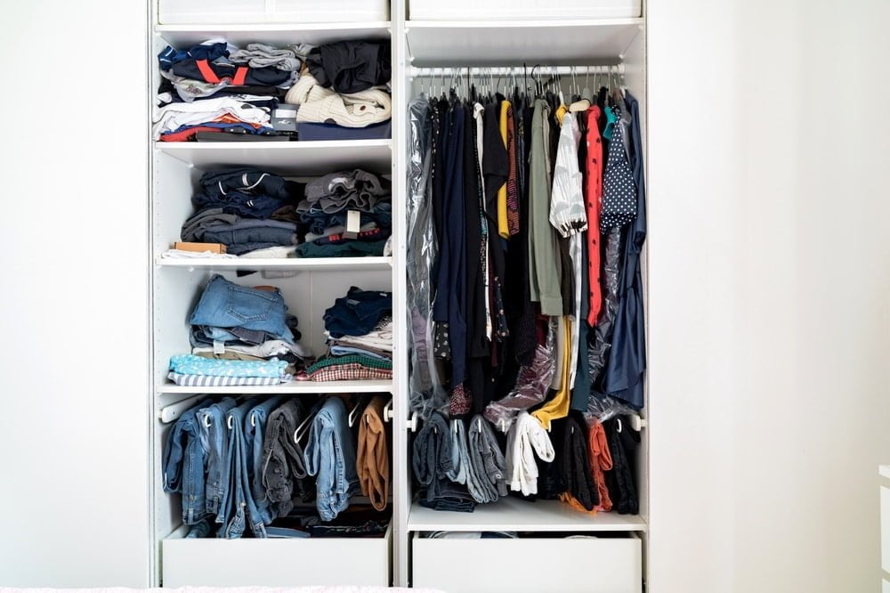 Open closet filled with clothes and has shelves