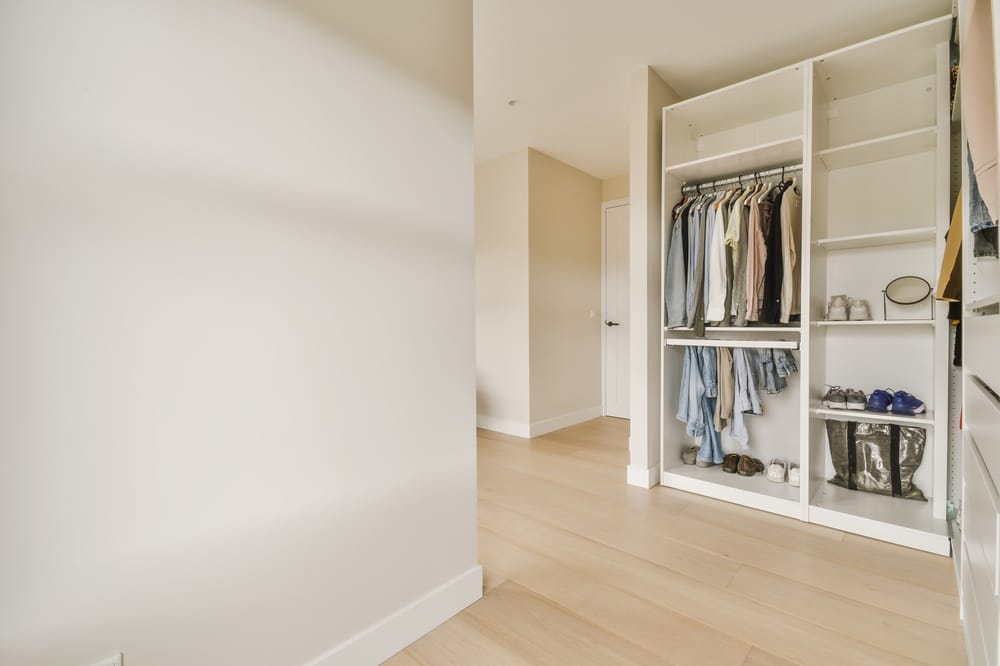 Open closet full of clothes in an empty room