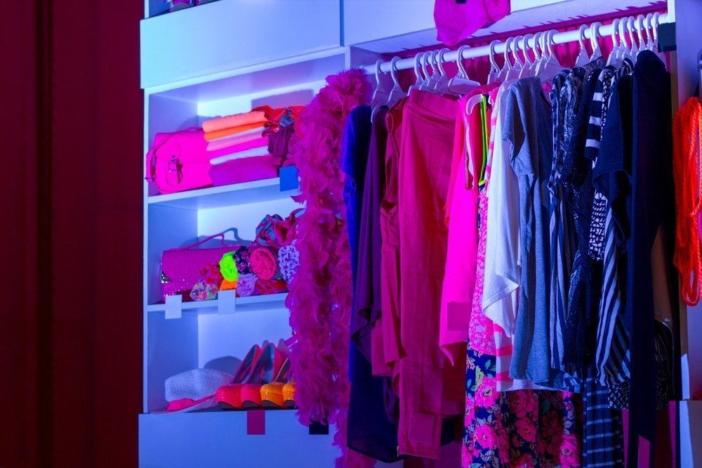 Open closet with pink and purple neon colored clothes and items on it
