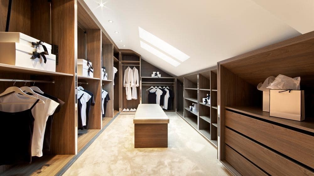 Walk in closet with dark wooden open shelves and small bench in the middle