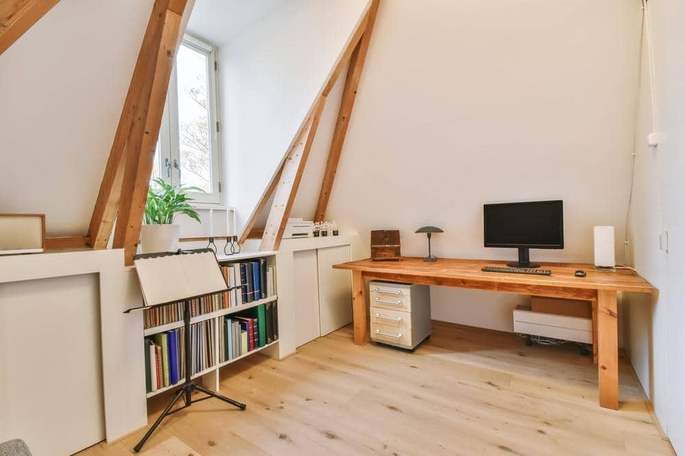 Wooden desk with a monitor in a small room with wooden floor