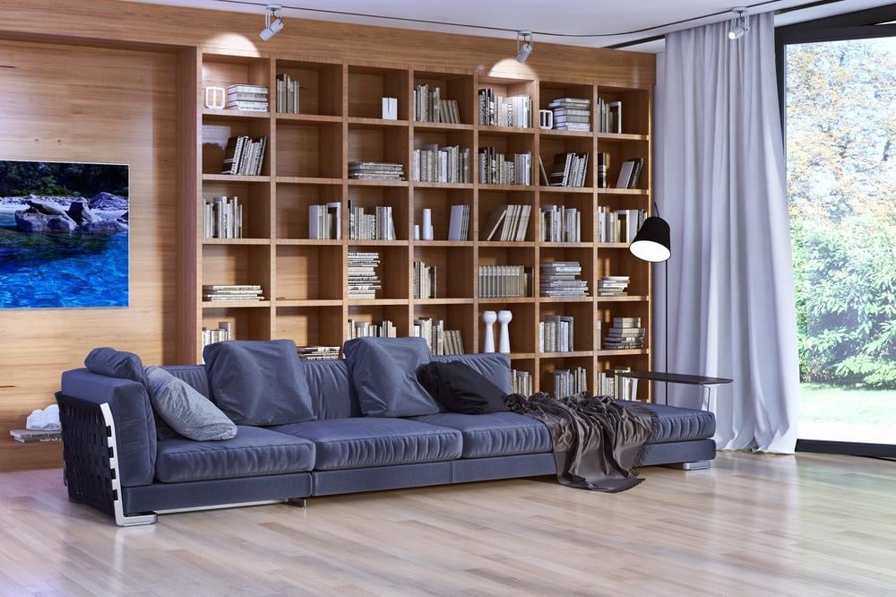 Room with large wooden bookcase and large sofa in front of it