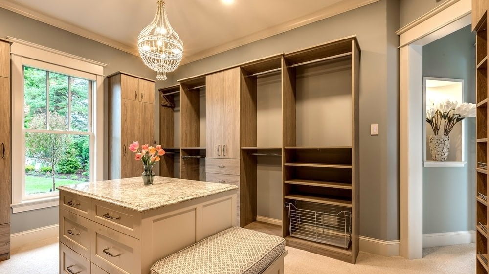 empty walk-in closet with marble counter island and chandelier