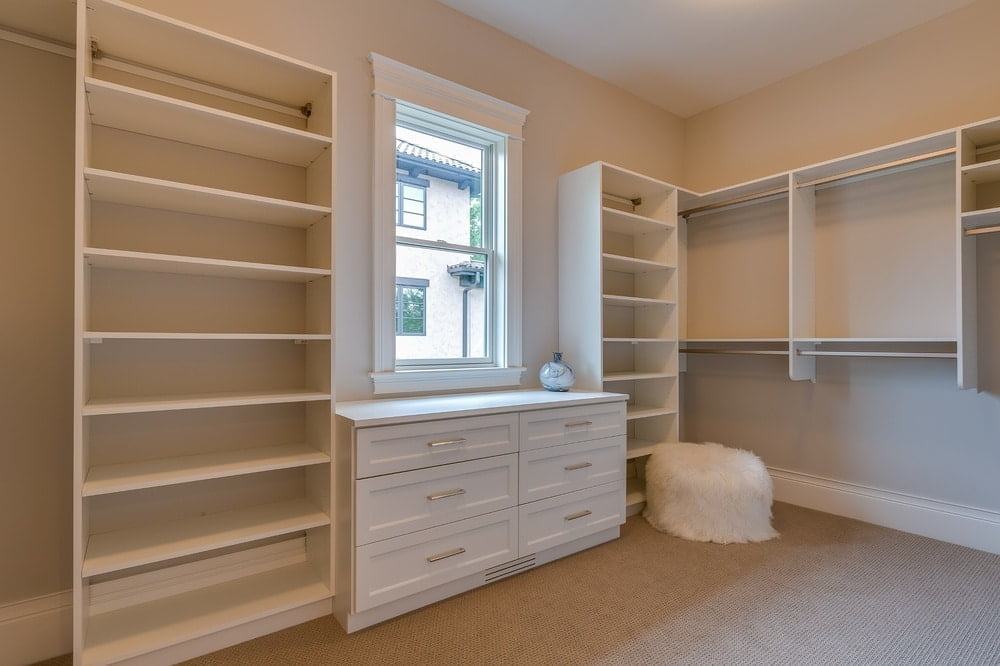 white empty walk in closet with drawers and hangers