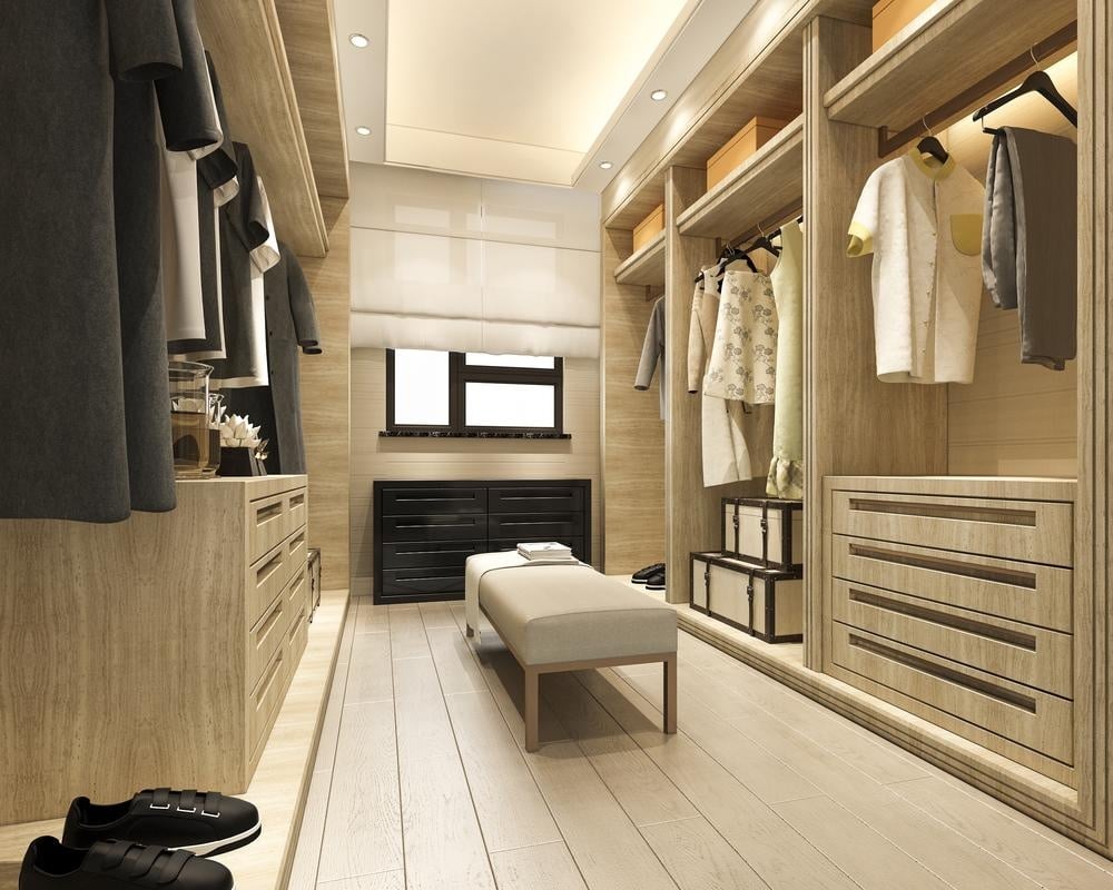 Modern luxurious walk in closet with a bench in the middle
