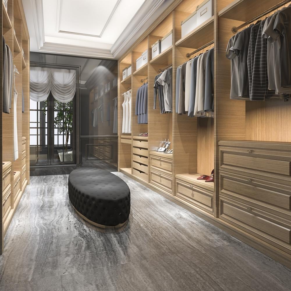 modern men's walk-in closet with wooden closets and black ottoman