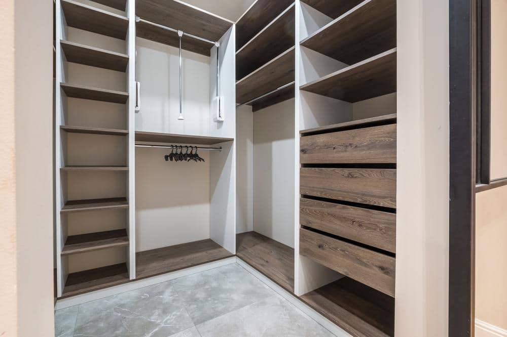 Empty walk in closet with open shelves racks and drawers