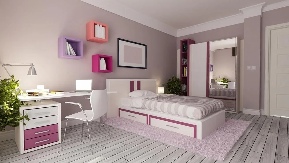 A room with pink furniture like bed frame and cabinets with white wooden floor