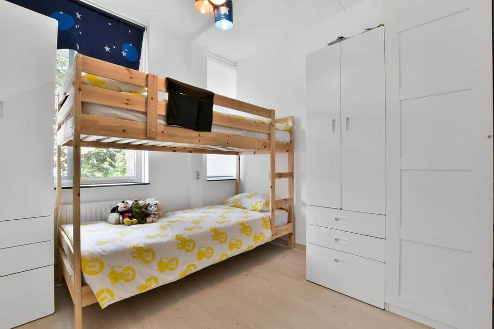 Twin wooden bed in a room with white cabinets