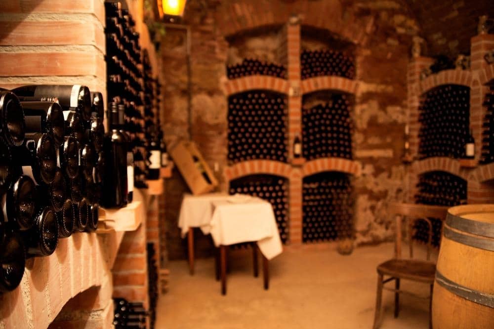 Stone wine cellar in a basement with serving table and wine bottles