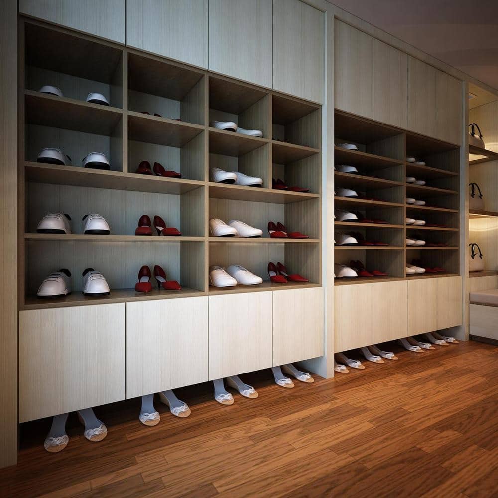 Built in closet with handleless cabinets and shoe racks that have shoes on them