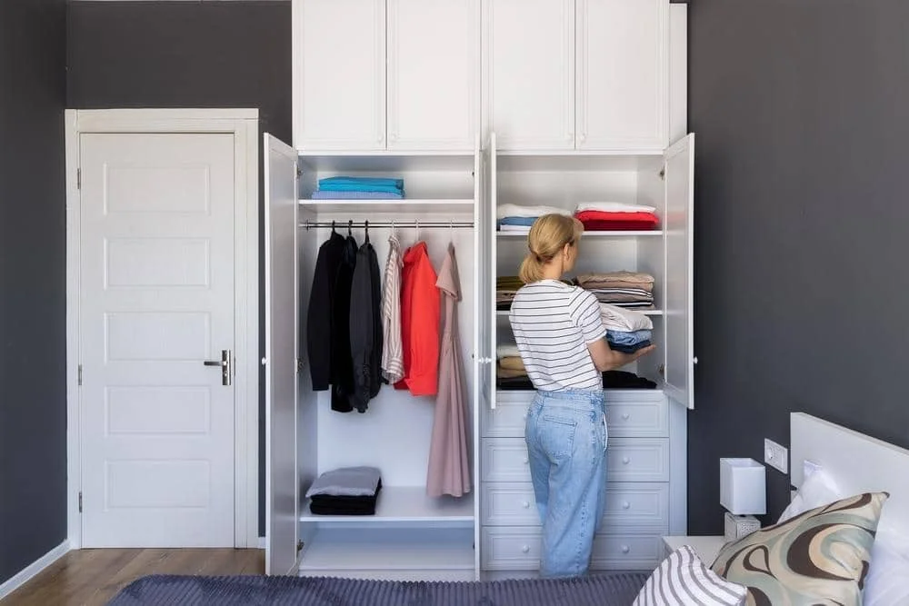 Woman folding clothes in front of a white reach in closet