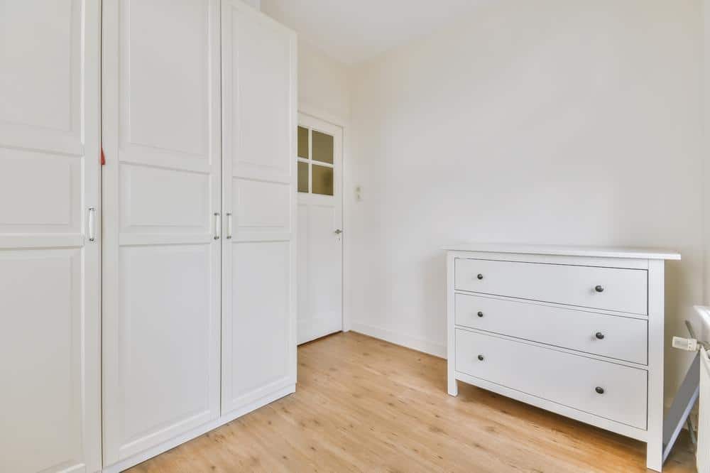 White standing closet and standing drawers in a room with wooden flooring