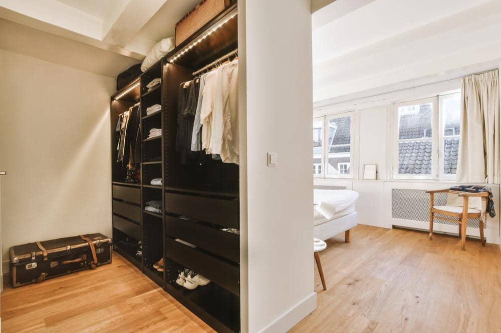 Black standing closet with open shelves in a bedroom with divider
