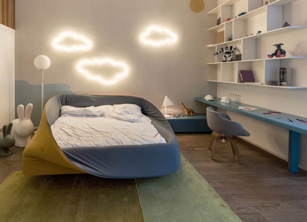 Organized modern kids room with wall lighting shaped like clouds and wall mounted desk with shelves