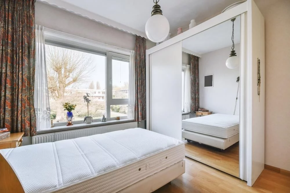 Step into Style: Knock them Dead with These 20 Eye-Catching Closet Door Ideas! 14 Windowed bedroom with a mirror door closet next to a bed