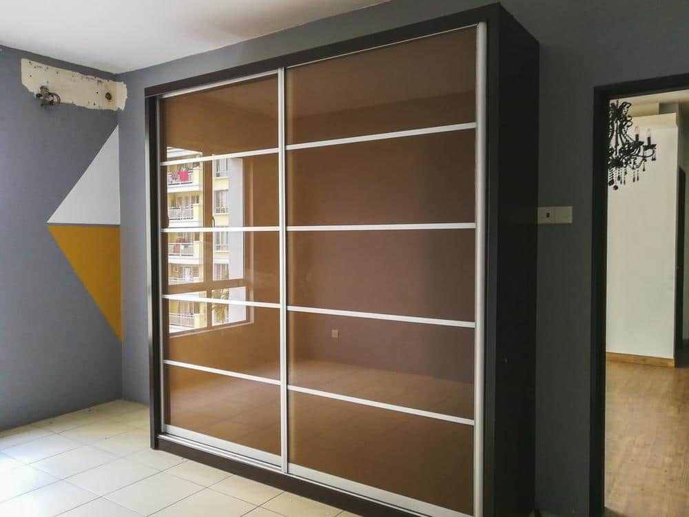 Standing closet with a brown sliding door in a room with grey walls