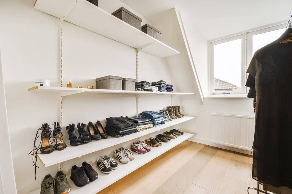 Light room with wall hung open shelves have shoes and boxes on them