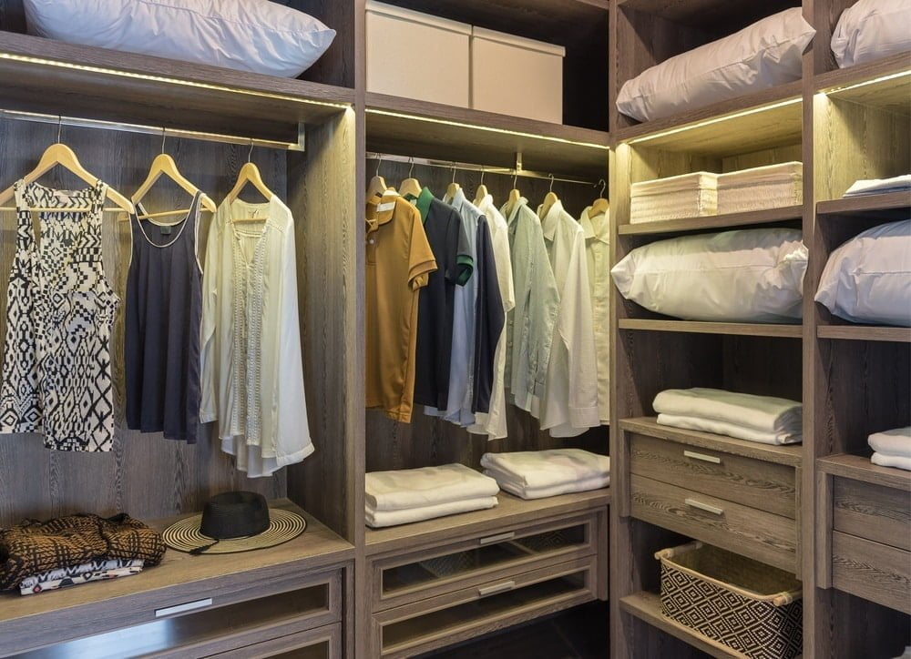 Wooden walk in closet with clothing racks and drawers