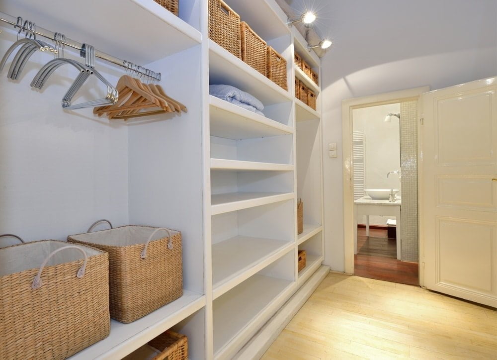 White empty built in closet with storage bins and hangers