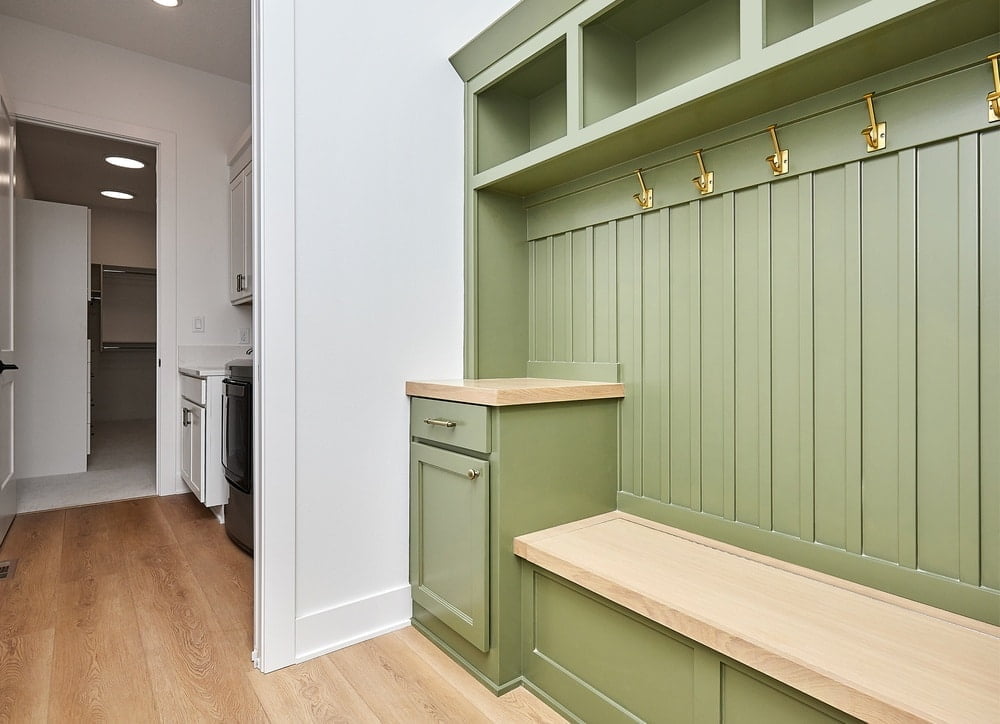Green mudroom with wooden bench and cabinet