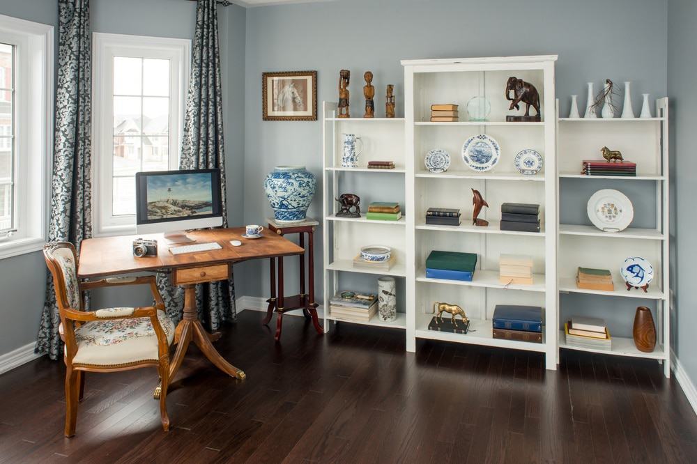 A room with white open shelves and a desk with a monitor on it