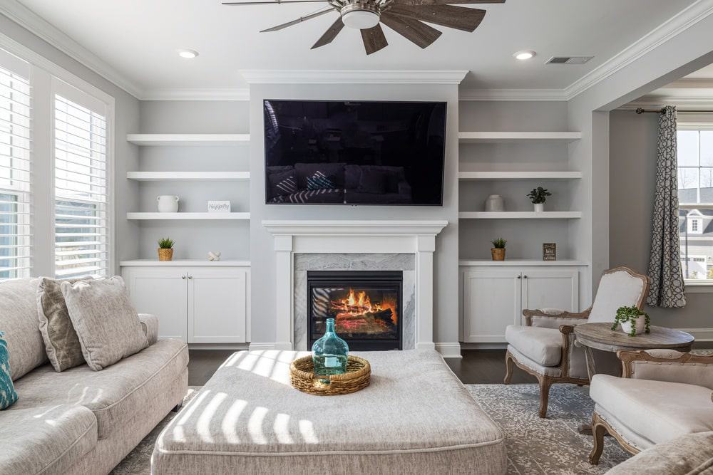 White living room with open shelves and tv hung on the wall
