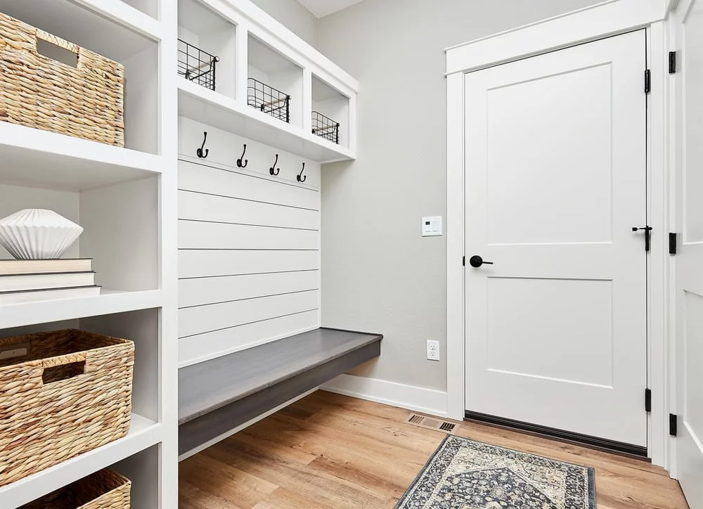white organized entryway with grey bench and coat hangers