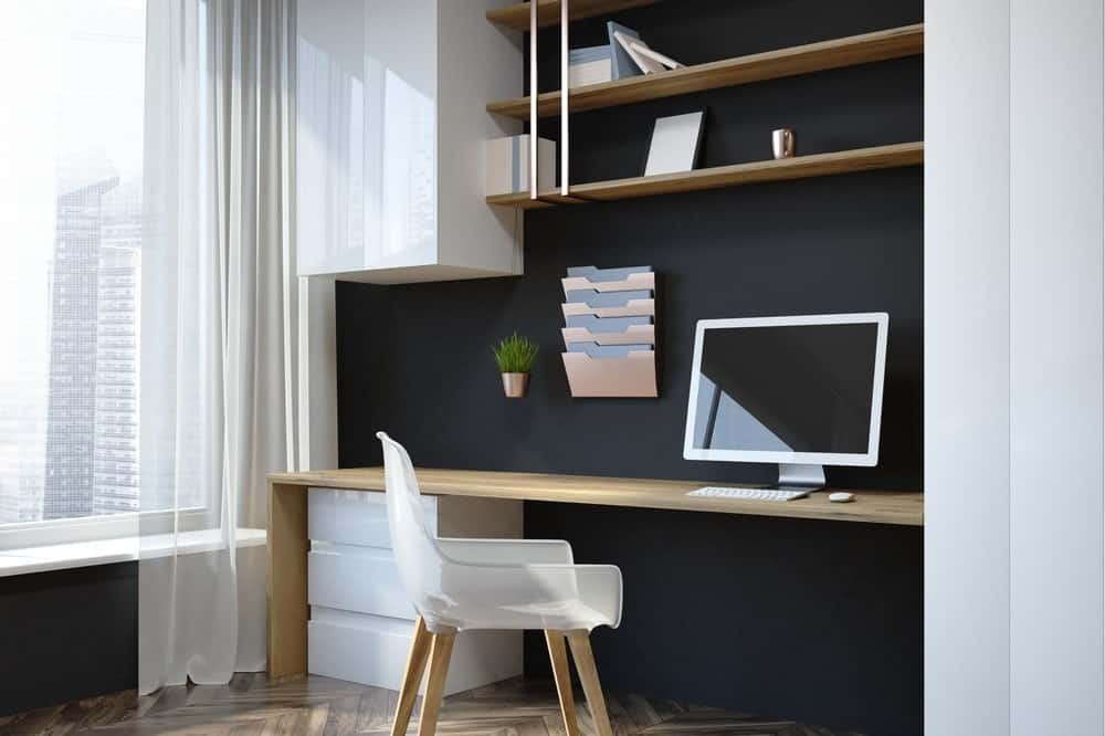 a desk with a white chair and a monitor with open shelves on top