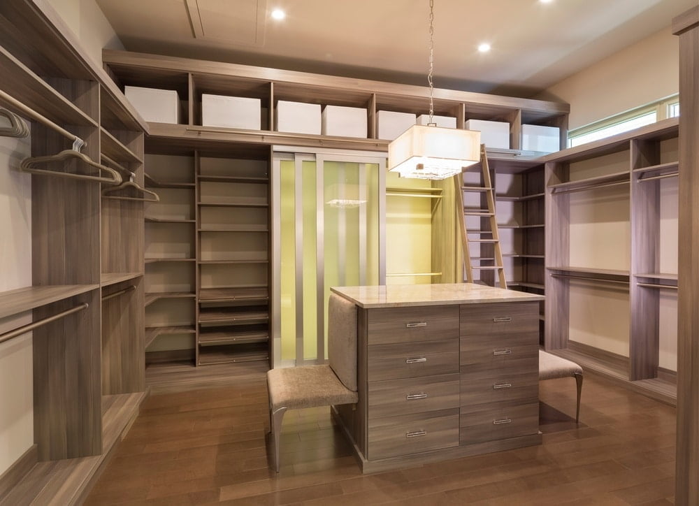 Modern wooden empty walk in closet with island and white closet