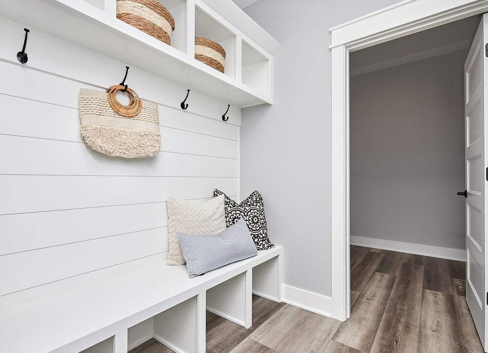 White mudroom with white bench and pillows on it