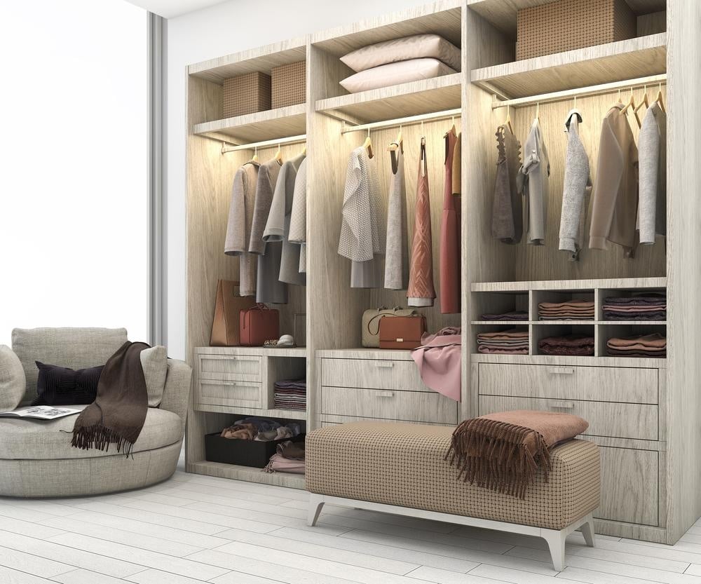 Modern standing closet full of clothes with ottoman and armchair