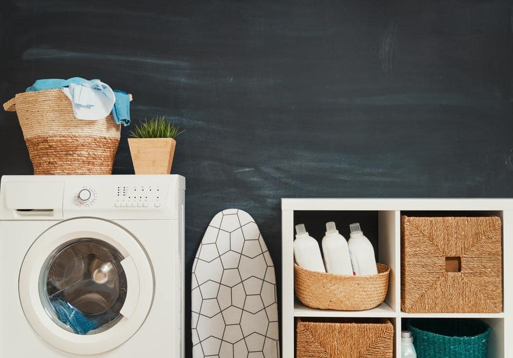 Washer next to laundry items such as ironing board and bins