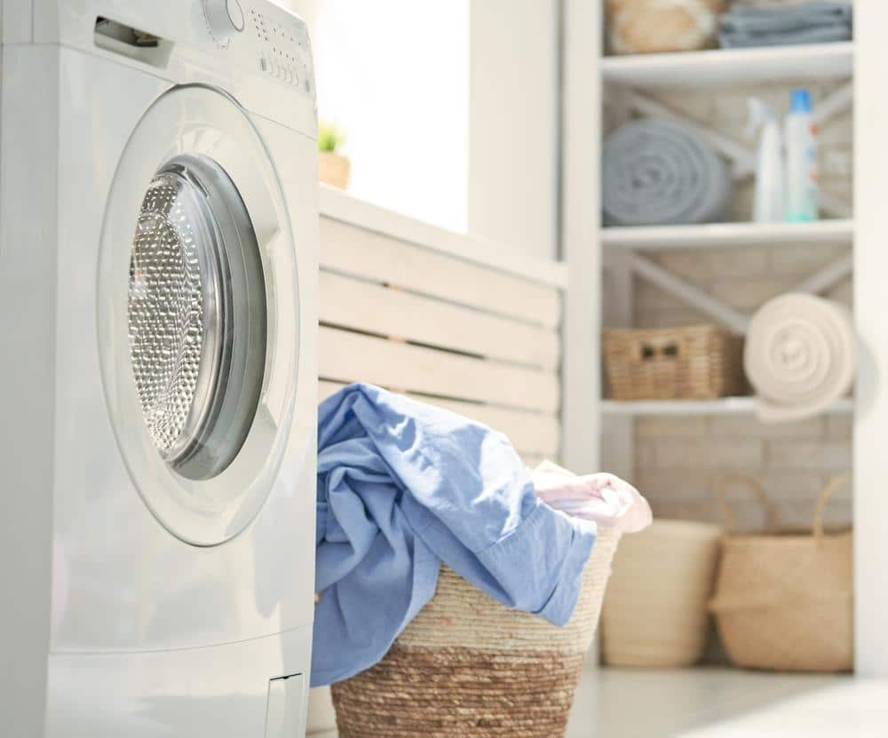 White lighted laundry room with washer and laundry basket
