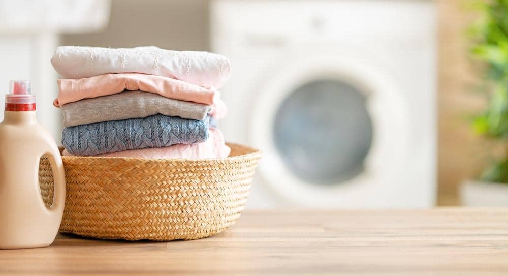 A basket full of folded clothes next to a detergent
