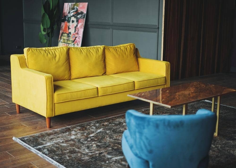 A yellow couch and a blue armchair in a room staying opposite