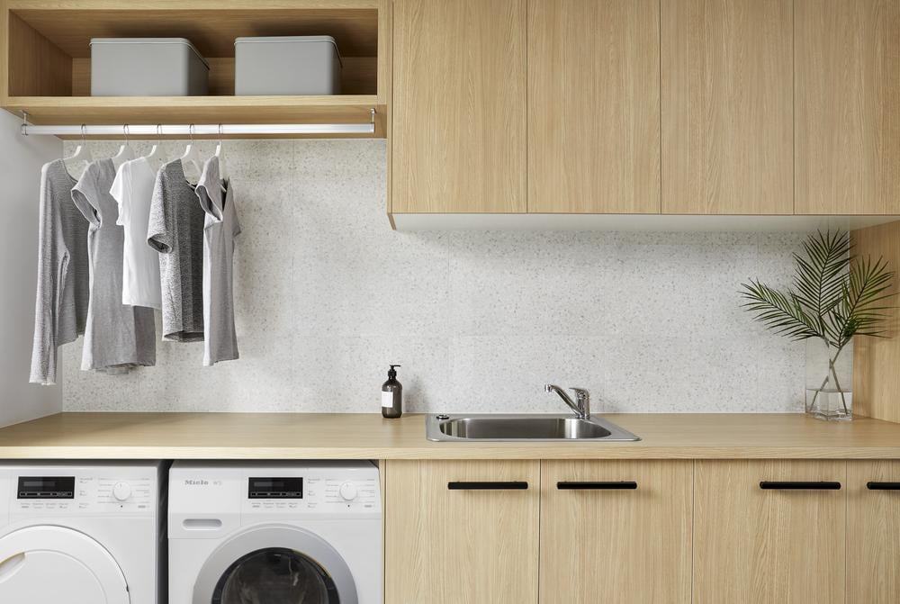 Washer and a dryer in a laundry room with wooden cabinets and counter