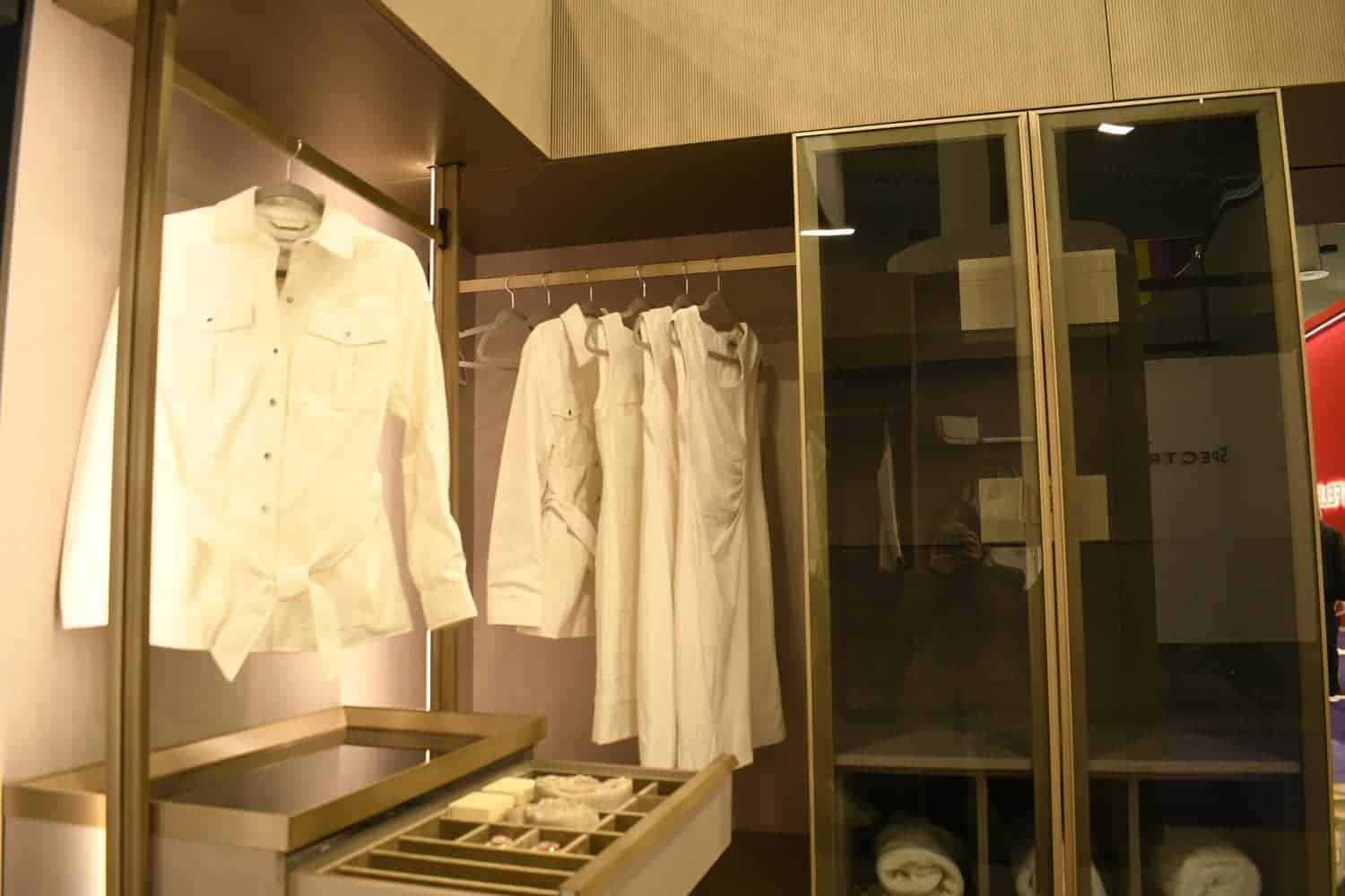 Glass door closet with hangers and white shirts on it