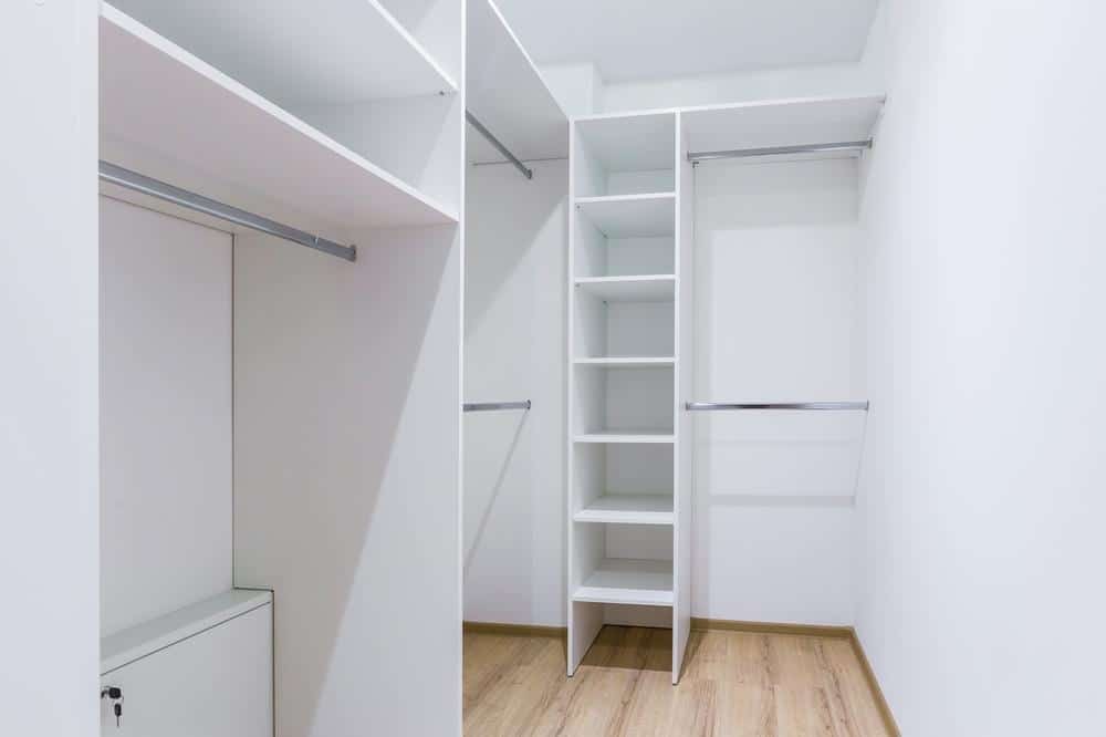 Small white and empty walk in closet with hangers